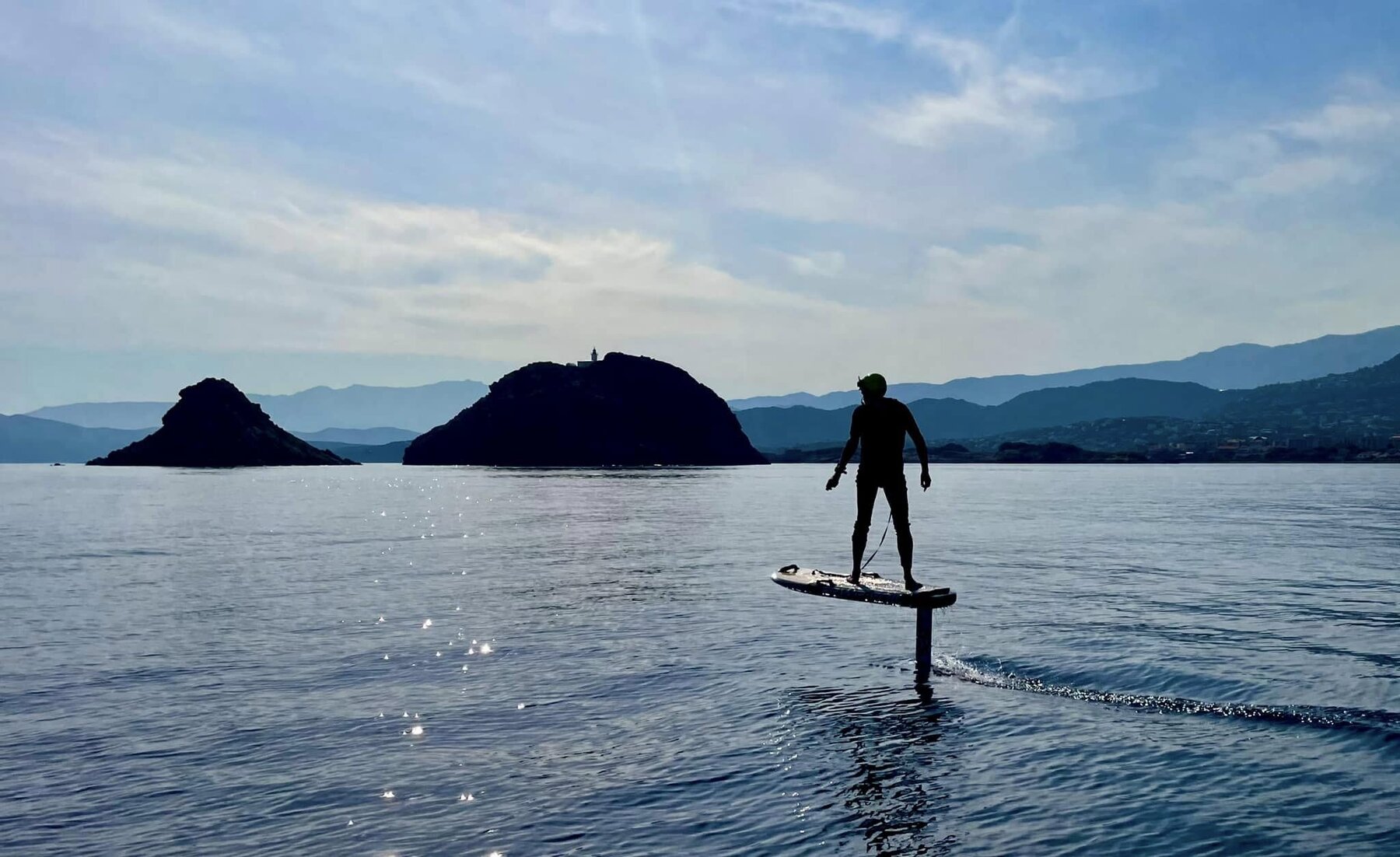 Élève Wingbox souriant allongé sur une planche eFoil dans la baie de L'Île-Rousse
